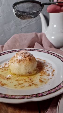 A short food video showing sugar being sprinkled on a sweet yeast dumpling topped with butter. 
