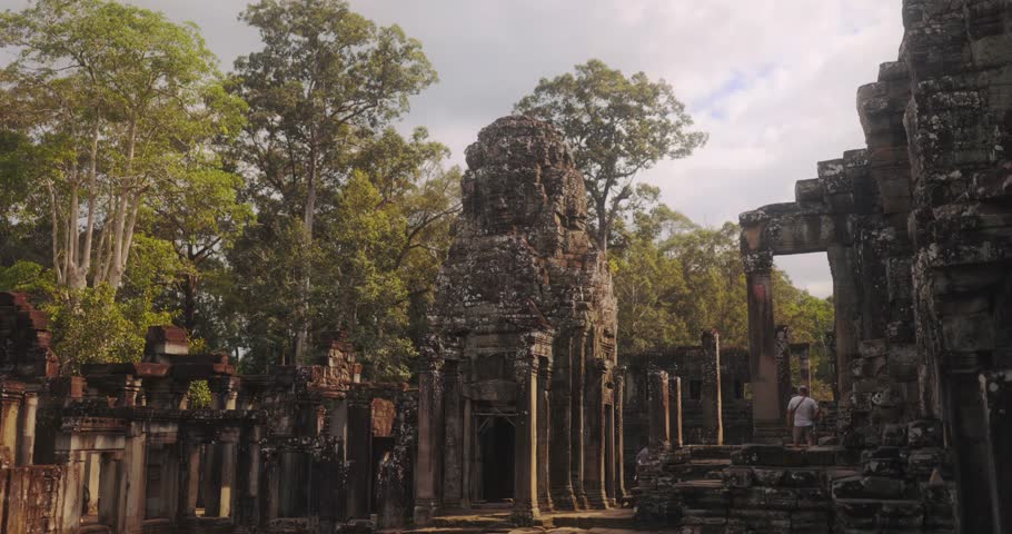 Beautiful view of Bayon Temple ruins framed by tropical forest in Angkor, Cambodia. Conceptual high quality footage for travel, history, archeology, culture, lifestyle, and global tourism advertising.