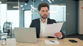 Handsome businessman in a suit analyzes complex documents in a modern office, showing confusion and concern. Diligently reviews papers, processing challenging information on laptop. - Powered by Shutterstock - Get 15% off with code: PIKWIZARD15