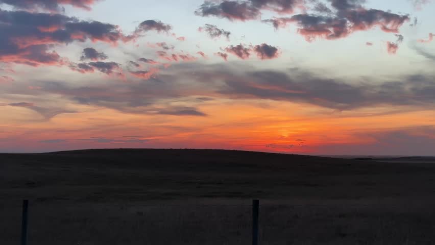 Majestic, Gorgeous, Beautiful Alberta, Canada, sunset sky, with vibrant orange and pink clouds over open prairie landscape, capturing the calm and colourful evening light across the rural horizon.