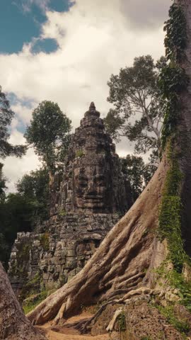 Stunning view of Bayon Temple faces surrounded by giant tree roots in Angkor Wat, Cambodia. Perfect for travel, history, promo, and cultural heritage footage in high quality 4K.