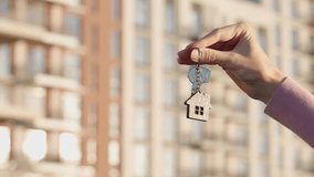 Close up of female real estate agent hand holding house key with home shaped keychain on background of apartment building, copy space. Real estate concept, property purchase, mortgage, housing service - Powered by Shutterstock - Get 15% off with code: PIKWIZARD15