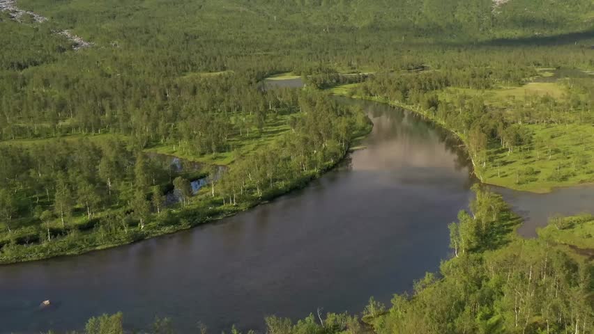 Aerial view of a winding river through a lush green forest and meadows.