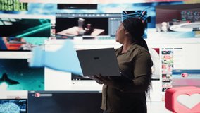 Woman uses laptop, enjoying leisure time with content on video streaming services. African american person watches media VOD broadcasts on notebook in front of digital backdrop with clips, camera A - Powered by Shutterstock - Get 15% off with code: PIKWIZARD15