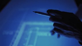 Dark silhouette of male hands with stylus over blueprint on a large touch screen - Powered by Shutterstock - Get 15% off with code: PIKWIZARD15