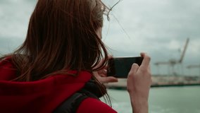 Unrecognizable woman filming sea with smartphone on ferry in Dunkirk port France. Female tourist recording ocean view near harbor cranes during boat ride. Person capturing waterscape while traveling - Powered by Shutterstock - Get 15% off with code: PIKWIZARD15