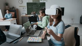 Teenage girl with prosthetic arm using VR glasses while other students working on laptops during It class in school - Powered by Shutterstock - Get 15% off with code: PIKWIZARD15