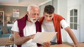 Proud grandfather and his smiling teenage grandson reading a document at home, celebrating great results and success with a high five, feeling happy and excited about the future - Powered by Shutterstock - Get 15% off with code: PIKWIZARD15