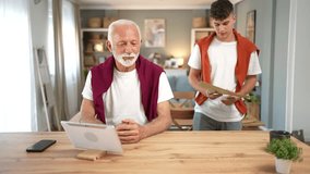 Happy grandfather and his college-aged grandson reading an important letter with good news from a university, celebrating successful exam results together at home while bonding and smiling - Powered by Shutterstock - Get 15% off with code: PIKWIZARD15
