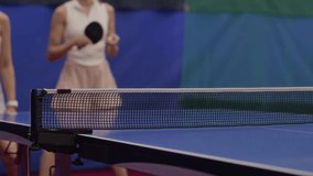 Two determined young women in tennis sportswear returning shots from same side of table while playing as doubles team in competition hall - Powered by Shutterstock - Get 15% off with code: PIKWIZARD15