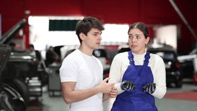 European guy consults with a car service worker about the repair and diagnostics of the car. Female mechanic gives recommendations for changing the oil, filter and checking the engine. High quality 4k - Powered by Shutterstock - Get 15% off with code: PIKWIZARD15