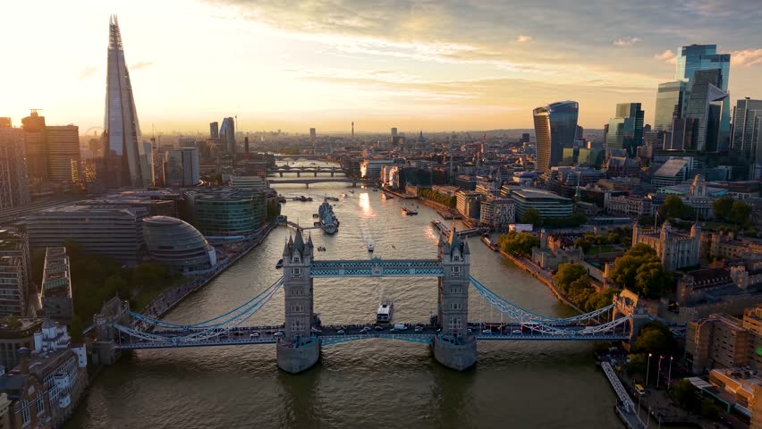 Beautiful, panoramic aerial view of the skyline of London, United Kingdom, along the Thames river with City and Tower bridge during golden sunset time