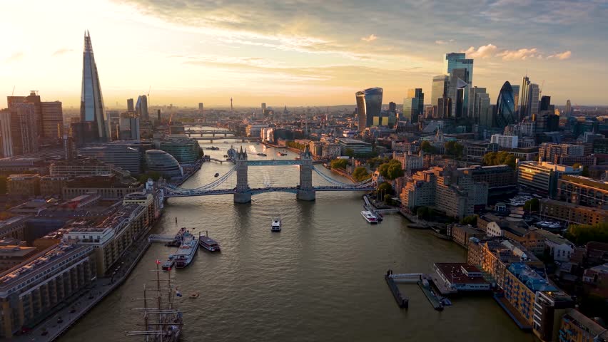 Beautiful, panoramic aerial view of the skyline of London, United Kingdom, along the Thames river with City and Tower bridge during golden sunset time
