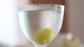 Cold, fogged martini glass filled with clear liquid and a green olive at the bottom - Powered by Shutterstock - Get 15% off with code: PIKWIZARD15
