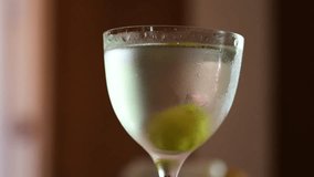Cold, fogged martini glass filled with clear liquid and a green olive at the bottom - Powered by Shutterstock - Get 15% off with code: PIKWIZARD15