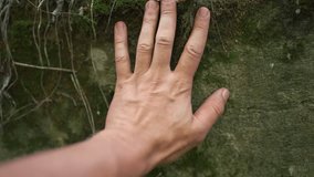 A man's hand rests on moss-covered rock, where the hand explores the rock's surface. The hand interacts with the natural texture of moss and rock in a serene setting. - Powered by Shutterstock - Get 15% off with code: PIKWIZARD15