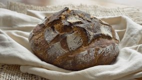 4K video of homemade sourdough bread loaf rotating from right to left on linen. Rustic artisan food shot, perfect for bakery, cooking, and culinary projects. - Powered by Shutterstock - Get 15% off with code: PIKWIZARD15