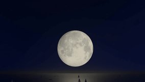 This video shows a full moon setting over the sea. The dark sky is filled with stars, and the silhouettes of sailboats are visible on the horizon. The moonlight reflects on the water, creating a - Powered by Shutterstock - Get 15% off with code: PIKWIZARD15