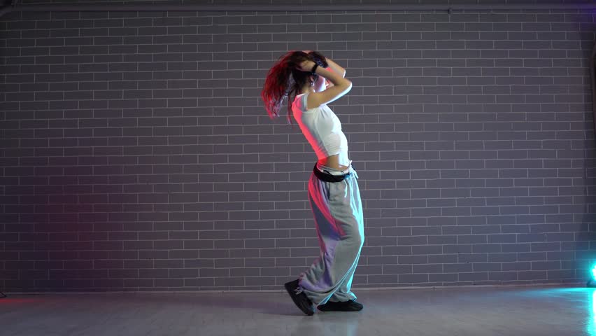 young girl choreographer dancing hip hop in neon lighting, woman performing on camera in and practicing dance jazz funk in dark studio