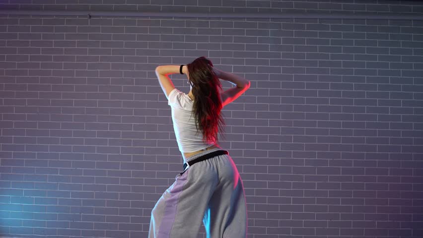 young girl choreographer dancing hip hop in neon lighting, woman performing on camera in and practicing dance jazz funk in dark studio
