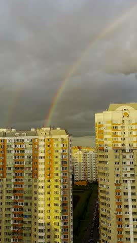 Moscow, Russia, 26.09.2025 Rainbow across a cloudy sky over residential multi-story buildings. Urban landscape with natural phenomenon, city life concept. Footage.
