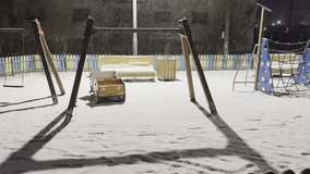 Snow gently falls on a quiet, illuminated playground at night - Powered by Shutterstock - Get 15% off with code: PIKWIZARD15