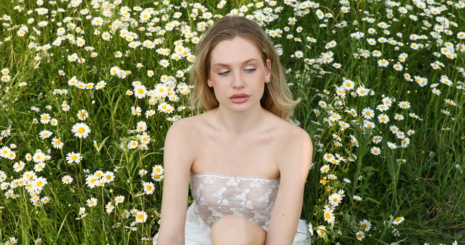 Young beautiful woman posing in a chamomile field