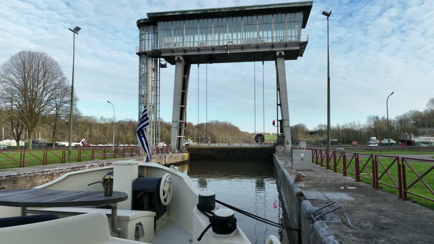 Aerial view of canal lock gate opening in Brussels, Belgium, with water movement and boat traffic on a sunny day.