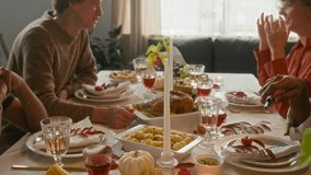 Black man lighting white long candle and two Caucasian friends chatting while sitting at festive table set with various dishes for thanksgiving party - Powered by Shutterstock - Get 15% off with code: PIKWIZARD15