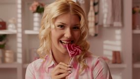 Caucasian teen girl female teenager woman in pink candy bathroom holding striped candy red lollipop appetizing bright in heart shape biting smiling tasty sugar diet food looking at camera indoors bite - Powered by Shutterstock - Get 15% off with code: PIKWIZARD15