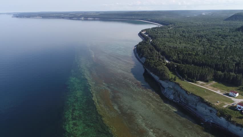Cliffs, Lighthouse, and Vast Forests overlook the Blue Waters at Pointe Carleton on Anticosti Island, where Coastline, Horizon, and Wilderness create a Majestic, Remote, and Scenic Panorama