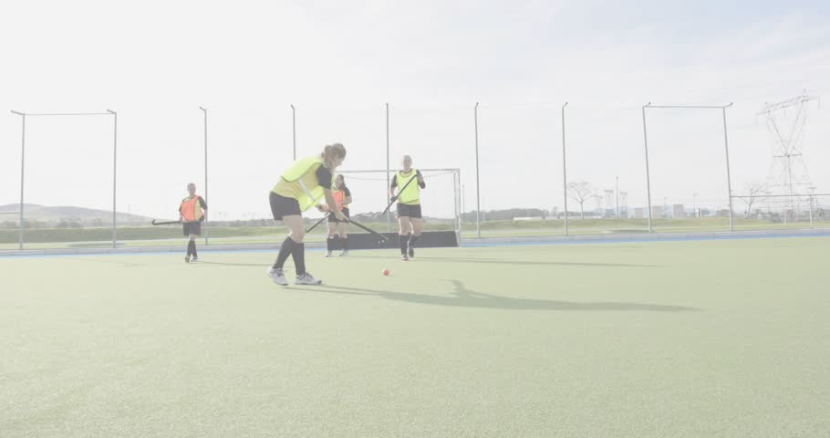 Field hockey drill opening with attacker placing ball on turf and dribbling, defender intercepting. Athletic, sports, teamwork, training, performance, outdoor, dynamic