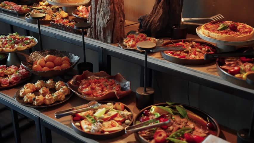 A luxurious buffet spread featuring an elegant selection of gourmet appetizers and finger foods, beautifully arranged on stylish platters for an upscale event or celebration.