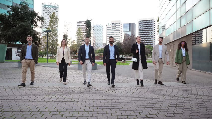 A diverse group of confident business professionals walking together, showcasing their teamwork and unity in a corporate setting while dressed in sophisticated business attire.