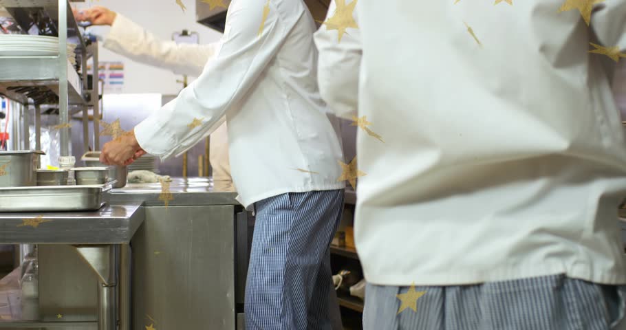 Chefs opening lower shelf at kitchen, exchanging pots while stirring and sliding trays for plating. Culinary, teamwork, stainless, industry, professional, preparation, organized