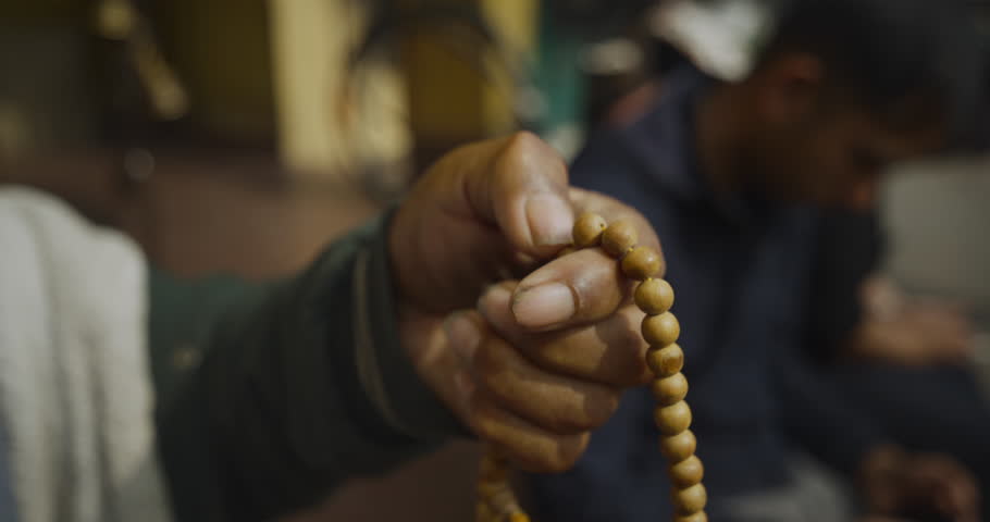 Buddhist devotee counts prayer beads (mala) during meditation at Boudha, Kathmandu, Nepal. Symbolic act reflects Buddhist culture, religion, faith, and spiritual devotion in a peaceful sacred setting