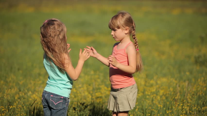 Two little girls clap their hands in flowers
