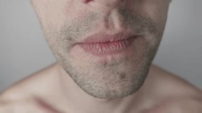 Extreme macro detail of a young man's mouth laughing heartily. Close-up shows pink lips, white teeth, and stubble on his chin and upper lip against an indistinct, neutral gray background. - Powered by Shutterstock - Get 15% off with code: PIKWIZARD15