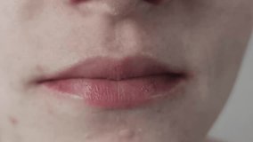 Macro close-up of a woman's mouth with glossy lipstick smiling gently. Detail shot shows imperfect skin texture with acne and freckles, expressing a subtle happy emotion on a plain background. - Powered by Shutterstock - Get 15% off with code: PIKWIZARD15