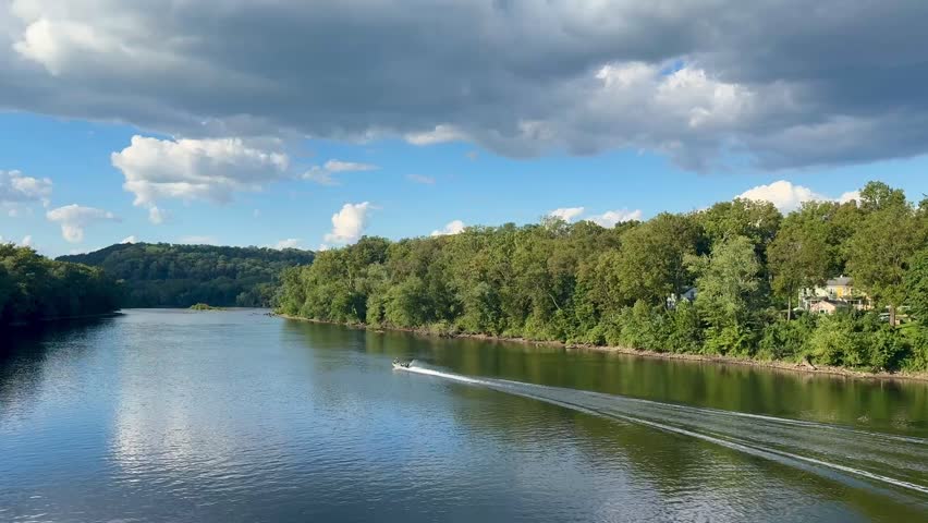 Aerial view of two people on small motor boat with front seat on Delaware River between Pennsylvania and New Jersey as seen from historic Riegelsville Free Bridge on summer afternoon in Bucks County