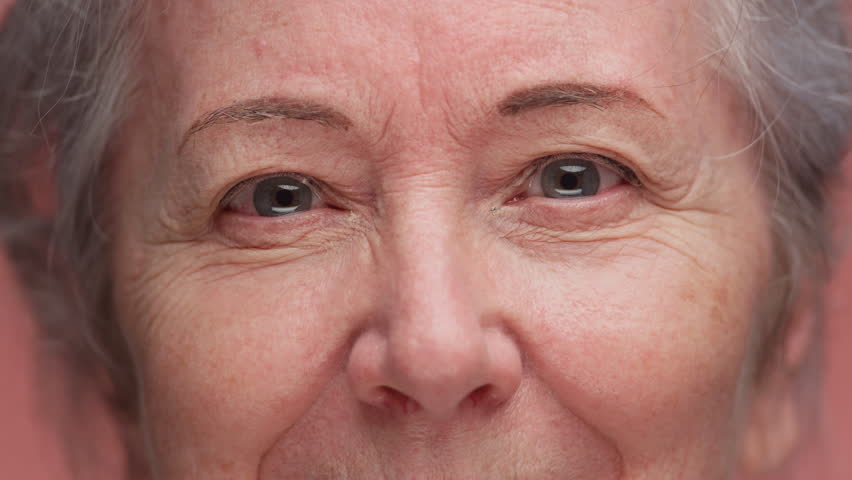 Extreme close-up of an older woman face as she slowly opens her eyes, showing emotion, detail, and natural aging.