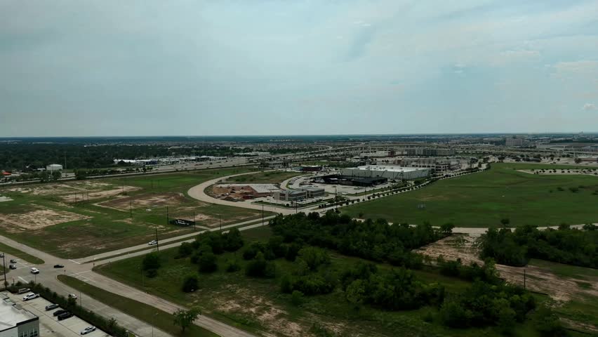 High altitude aerial drone video of a suburban area in Katy, Texas, showing a major highway intersection surrounded by residential and commercial zones on a clear day.