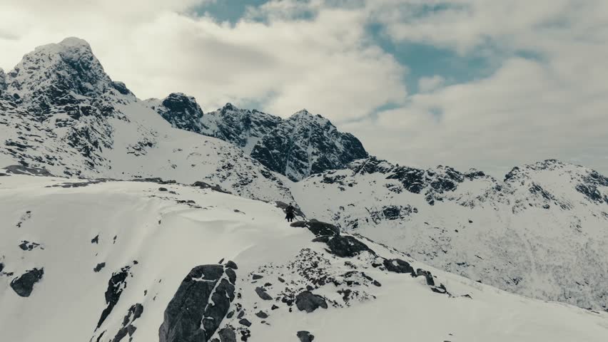 Hiker Climbs On Top Of The Snowy Mountain In Norway. - aerial shot