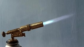 A stunning close-up of a golden propane jet torch igniting, producing an intense blue flame against a deep black background. Perfect for welding, DIY, cooking, and high-quality industrial  - Powered by Shutterstock - Get 15% off with code: PIKWIZARD15