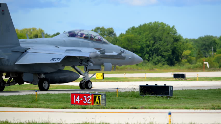 Slow motion close up rear view of F-18 fighter jet taxis heading to takeoff runway, showing military strength, speed, and precision.