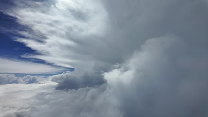 The sky is filled with fluffy white clouds, and the sun is peeking through them, creating a serene and tranquil atmosphere. The clouds are scattered throughout the sky, with some larger