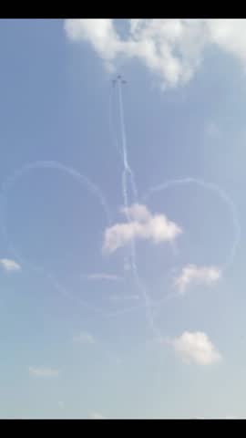 four jet planes in a line formation emitting white smoke and forming a symbol that resembles a heart
