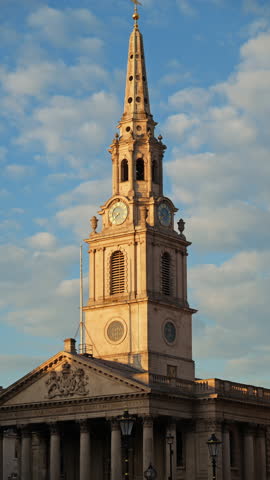 Tall clock tower of the St Martin-in-the-Fields church captured under a partly cloudy sky in London, England. Vertical