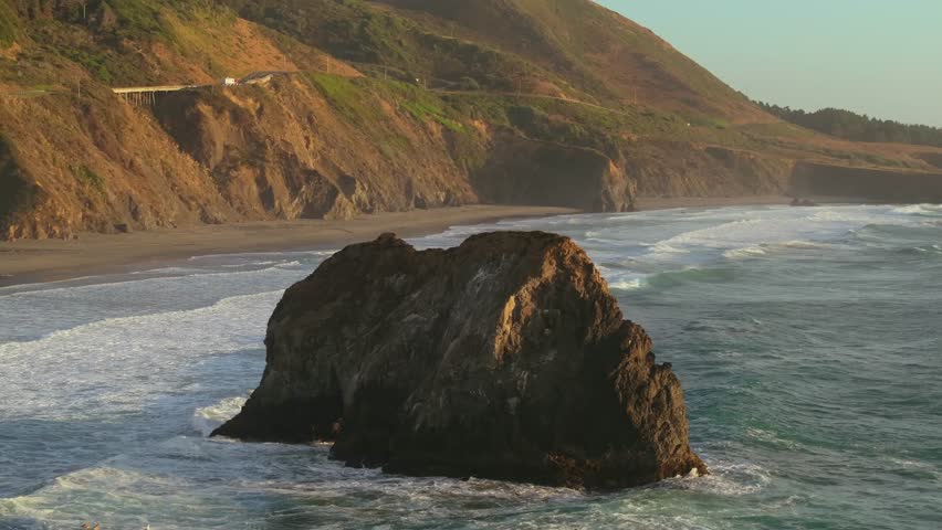 Golden sunlight on the California coast with waves and cliffs