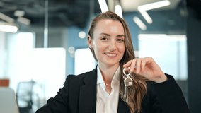 Confident businesswoman in a black blazer and white shirt smiles, presenting house keys in a modern office. Successful woman expresses joy about property ownership, real estate or relocation. - Powered by Shutterstock - Get 15% off with code: PIKWIZARD15